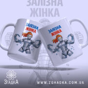 Чашка залізна жінка, біла з кольоровим принтом, дві чашки в центрі, фон світло-сірий, принт з малюнком залізної жінки з червоним волоссям, ручки класичні, краї рівні, глянцева поверхня.