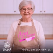 Фартух леді на кухні, бежевого кольору, зображений на манекені, фон однотонний, принт з написом 'Леді на кухні' та малюнком ножа в рожевих відтінках.