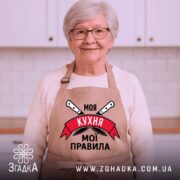 Фартух моя кухня мої правила. Фартух бежевого кольору, зображений з фронтального ракурсу на манекені. Фон світлий, без зайвих деталей. Принт містить напис 'Моя кухня мої правила' на червоному банері з зображенням ножів.