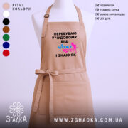 Фартух можу і хочу, бежевого кольору, зображений на манекені, фон нейтральний, принт чорного кольору з яскравими елементами синього та рожевого.