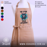 Фартух не стій над душею, бежевого кольору, зображений з близького ракурсу на манекені, фон однотонний, принт з малюнком кота з сокирою та текстом.