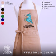 Фартух пташка трудоголічка, бежевого кольору, зображений на манекені, фон світлий, принт з пташкою, що тримає каву, з виразом трудоголіка.