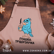 Фартух пташка трудоголічка, бежевого кольору, зображений на дерев'яному фоні, принт з пташкою, що тримає каву, з димком над чашкою, декор у вигляді новорічних елементів.