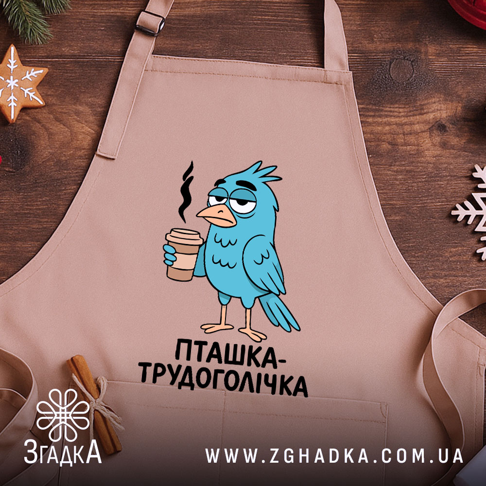 Фартух пташка трудоголічка, бежевого кольору, зображений на дерев'яному фоні, принт з пташкою, що тримає каву, з димком над чашкою, декор у вигляді новорічних елементів.