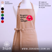 Фартух цілуюся краще ніж готую, бежевого кольору, зображений з фронтального ракурсу на манекені, фон однотонний, принт з червоними губами та текстом чорного кольору.