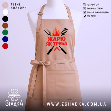 Фартух жарю як треба, бежевого кольору, зображений на манекені з ракурсу спереду, фон світлий, принт з червоним текстом та графічними елементами у вигляді вогню та кухонних інструментів.