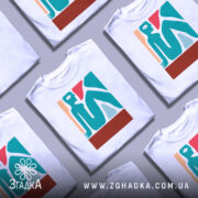 Футболка абстрактне арт зображення, біла, зображена на манекені, фон світло-сірий, принт містить стилізовану фігуру людини в блакитному, червоному та бежевому кольорах.