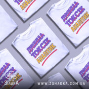 Футболка аналітик не токсік, біла, зображена на манекені, фон світло-сірий, принт містить текст "ДИШИНА ТОКСІК АНАЛІТИК" з перекресленим словом "ТОКСІК", кольори фіолетовий та жовтий.