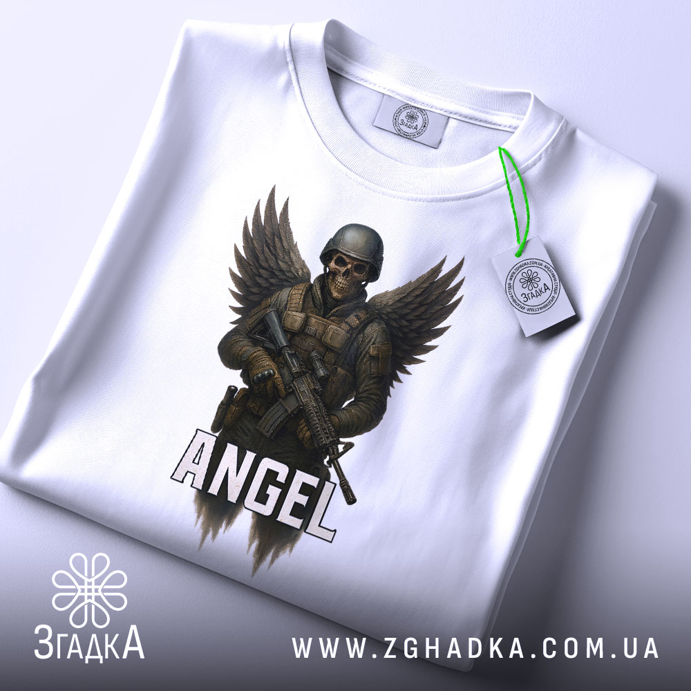 Футболка ангел боєць білого кольору, складена на столі, фон світло-сірий, принт з зображенням ангела-борця з крилами та автоматом, напис 'ANGEL' під малюнком, на футболці є етикетка з зеленим шнурком.