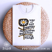 Футболка антивоєнна позиція, біла, складена на плетеній кошику, фон білий, принт з жовтою квіткою та текстом чорного кольору.