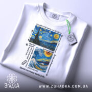 Футболка арт художній, біла, зображена на столі, фон світлий, принт містить зображення зірок, ночі та океану з текстом на англійській мові, на комірці є етикетка.