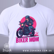 Футболка байкер мама сила. Біла футболка, складена на поверхні, з принтом жінки на мотоциклі, ракурс зверху, фон світло-сірий, принт яскравий з червоним і чорним кольорами.