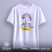 Футболка безсмертний поні, білого кольору, підвішена на вішалці, фон світло-сірий, принт з веселим поні, що тримає райдужні стрічки, текст чорного кольору з жовтим акцентом, вільний крій.