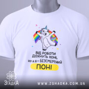 Футболка безсмертний поні, білого кольору, розкладена на поверхні, фон світло-сірий, принт з поні, що радісно піднімає руки, текст чорного кольору з жовтим акцентом, на комірці видна етикетка.