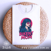 Футболка BIKENT MOM білого кольору, зображена з верхнього ракурсу, складена на плетеній основі, фон світлий, принт з дівчиною в сонцезахисних окулярах та текстом 'BIKENT MOM' в яскравих кольорах.