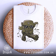 Футболка бойовий кіт, біла, складена на кошику, фон світло-сірий, принт з кумедним котом у військовій кепці та окулярах, тримає кулемет з патронами.