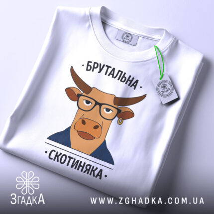Футболка брутальна скотиняка, білого кольору, зображена зверху на плоскій поверхні, фон світлий, принт з ілюстрацією корови в окулярах та піджаку, прикріплена етикетка з зеленим шнурком.