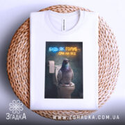 Футболка будь як голуб, білого кольору, з верхнього ракурсу, на фоні плетеного кошика, з принтом, що зображує голуба на унітазі, з написом 'БУДЬ ЯК ГОЛУБ - СРИ НА ВСЕ' у неоновому стилі.