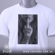 Футболка бунтарський арт, біла, складена на столі, фон світло-сірий, принт у чорному та білому кольорах з дівчиною, що показує середній палець, на футболці є етикетка з логотипом.