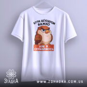 Футболка бути абʼюзером білого кольору, зображена з фронтального ракурсу, фон світло-сірий, принт з карикатурним птахом, текст чорного кольору зверху і оранжевого знизу.