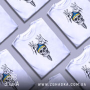 Футболка череп воїн, біла, зображена з фронтального ракурсу на манекені, фон світло-сірий, принт з черепом у блакитній шапці з жовтою смужкою та жестами рук.