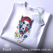 Футболка Череп Вовка, біла, складена на столі, фон світло-сірий, принт з черепом вовка у червоній шапці, з язиком, що стікає, з елементами в кольорі.