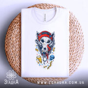 Футболка Череп Вовка, біла, складена на плетеному кошику, фон білий, принт з черепом вовка у червоній шапці, з язиком, що стікає, з кольоровими елементами.