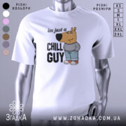 Футболка chill guy стиль, біла, зображена з фронтального ракурсу на манекені, фон світло-сірий, принт з мультяшним персонажем ведмедя у джинсах та светрі, текст 'im just a CHILL GUY'.