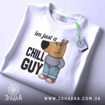 Футболка chill guy стиль, біла, зображена зверху, складена, фон світло-сірий, принт з мультяшним ведмедем у джинсах та светрі, текст 'im just a CHILL GUY', на комірці видна етикетка.