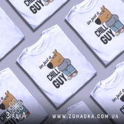 Футболка chill guy стиль, біла, зображена з фронтального ракурсу на манекені, фон світло-сірий, принт з мультяшним персонажем ведмедя у джинсах та светрі, текст 'im just a CHILL GUY'.