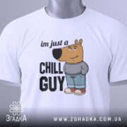 Футболка chill guy стиль, біла, зображена зверху, складена, фон світло-сірий, принт з мультяшним ведмедем у джинсах та светрі, текст 'im just a CHILL GUY', на комірці видна етикетка.