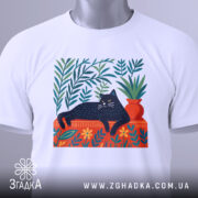 Футболка Чорний кіт спокою білого кольору, зображена зверху, складена на поверхні, фон світло-сірий. Принт з чорним котом, що лежить на червоній підставці, оточений зеленими рослинами та квітами, з етикеткою на рукаві.