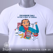 Футболка Далі арт принт, біла, зображена зверху, фон світло-сірий, принт з ілюстрацією Сальвадора Далі, який їсть з миски, з деталями молока, бананів і коробки з написом 'Surreal', на комірці видна етикетка.