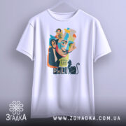 Футболка Далі арт, біла, підвішена на вішалці, фон світло-сірий, принт з обличчям художника, кольорові деталі, текст "I don't do drugs I AM drugs" та чорна кішка.