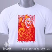 Футболка демон червоний, біла футболка на плоскій поверхні, ракурс зверху, фон світло-блакитний, принт з червоним демоном та черепами, з етикеткою на зеленому шнурку.