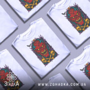 Футболка демонічний яскравий образ, біла, з фронтальним ракурсом, на манекені, фон світло-сірий, принт з червоним демоном, жовтими черепами та чорними кістками, оточений фіолетовими і зеленими елементами.