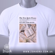 Футболка дівчата читають книги, біла, з верхнього ракурсу, складена на поверхні, фон світлий, принт у стилі газети з текстом 'HOT GIRLS READ BOOKS' та зображенням книги з навушниками.