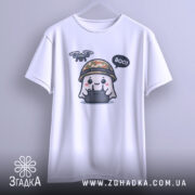 Футболка Дрон під контролем, біла, підвішена на вішалці, фон світло-сірий, принт з веселим привидом у камуфляжному шоломі, який тримає пульт управління з дроном, текст 'BOO!' у бульбашці.