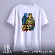 Футболка дружина воїна ЗСУ, біла, підвішена на вішалці, фон світло-сірий, принт з жінкою в капюшоні та військовим, кольори принта: жовтий, синій, зелений.