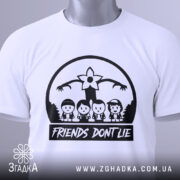 Футболка друзі не брешуть, біла, складена на столі, фон світло-сірий, принт чорного кольору з персонажами та написом 'FRIENDS DON'T LIE', на футболці є етикетка з зеленим шнурком.