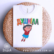 Футболка душніла білого кольору, складена на плетеній основі, з принтом, що зображає персонажа, який тримає напис "Душніла". Фон світлий, деталі принта яскраві.