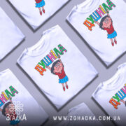 Футболка душніла білого кольору, зображена на манекені, з принтом, що зображає персонажа, який тримає напис "Душніла". Фон світлий, деталі принта яскраві і кольорові.