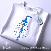 Футболка душніла білого кольору, складена на поверхні, з видимим етикеткою, фон світло-сірий, принт з душем та написом "Душніла" синього кольору, розташований по центру.