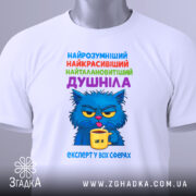 Футболка душніла експерт, біла футболка з принтом, зображення кота з блакитною шерстю, що тримає жовту чашку, текст на футболці кольоровий: синій, зелений, фіолетовий, червоний, вид з близька, на футболці є етикетка.