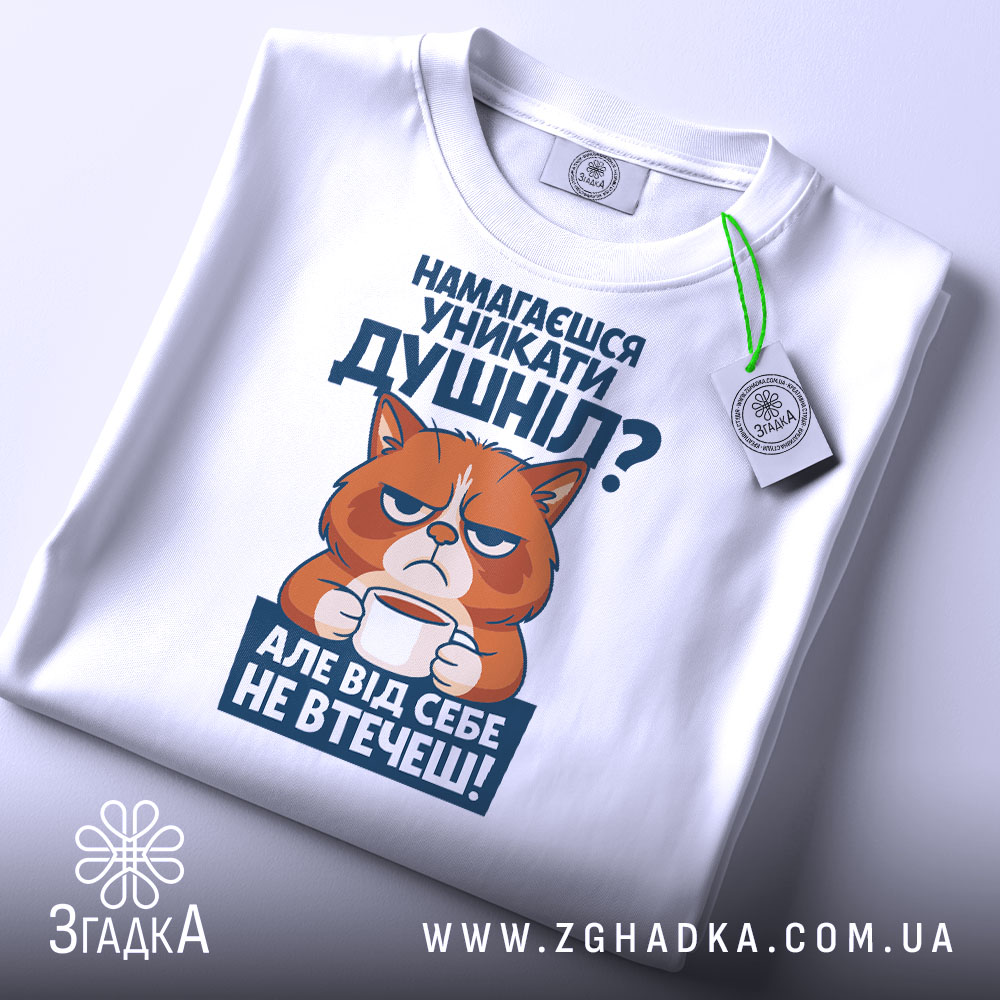 Футболка душніла білого кольору, зображена з верхнього ракурсу, фон світло-сірий, принт з котом, що тримає чашку, текст на принті синього кольору, на футболці є етикетка з зеленим шнурком.