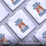 Футболка душніла білого кольору, зображена з фронтального ракурсу на манекені, фон світло-сірий, принт містить зображення кота з серйозним виразом обличчя, що тримає чашку, текст на принті синього кольору.