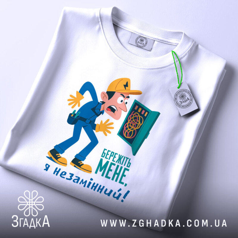 Футболка електрик незамінний, біла, зображена в горизонтальному ракурсі, фон світлий, принт з комічним персонажем в жовтій кепці, що тримає електричний щиток, текст на принті синій, на футболці є етикетка з зеленим шнурком.