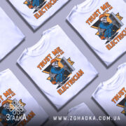 Футболка електрик білого кольору, зображена з фронтального ракурсу на манекені, фон світло-сірий, принт з малюнком скелета-електрика в синій робочій формі, що працює з електричним щитом, текст на принті яскраво-оранжевий.