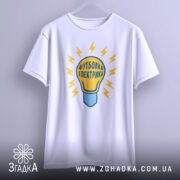 Футболка електрика 220 вольт, біла, підвішена на вішалці, фон світло-сірий, принт у вигляді лампочки з жовтими блискавками та написом 'Футболка електрика'.