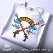 Футболка Fish Hunter білого кольору, зображена в складеному вигляді, фон світло-сірий, принт з двома рибальськими рушницями, рибами та написом 'FISH HUNTER', на етикетці зелена стрічка.